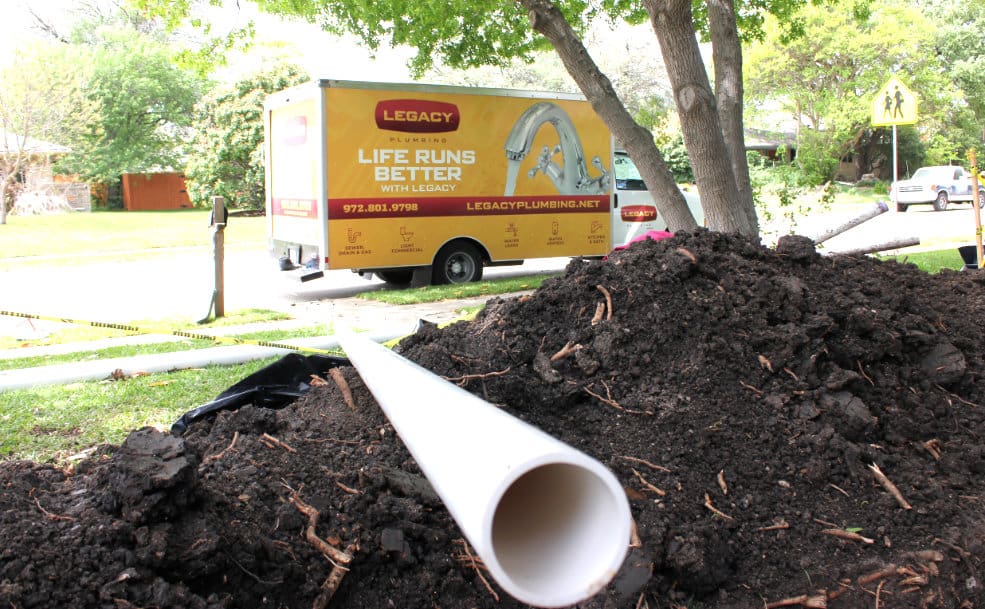 Legacy Plumbing truck outside of a home near a pile of a dirt with a new pipe to be installed