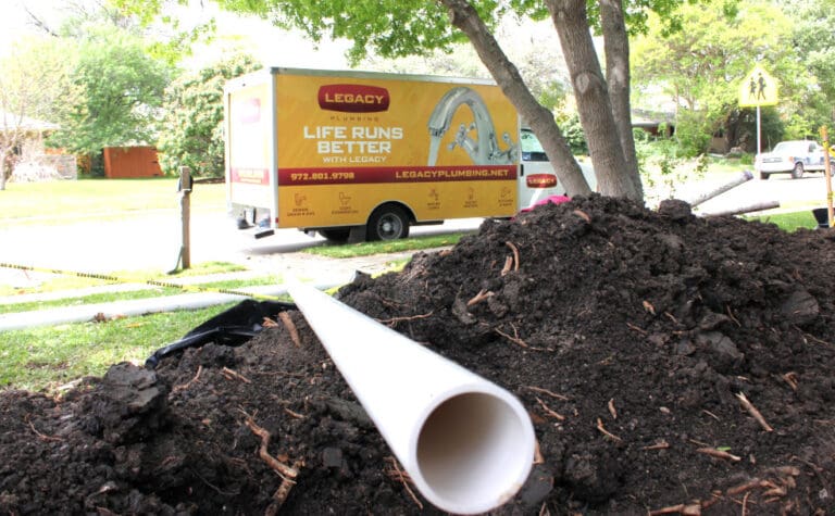 Legacy Plumbing truck outside of a home near a pile of a dirt with a new pipe to be installed