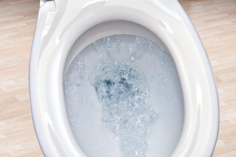Toilet bowl flushing water in bathroom close up.